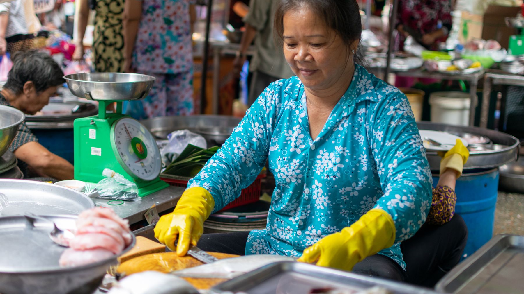 Asian woman selling fresh fish at a bustling market in Ho Chi Minh City, Vietnam.