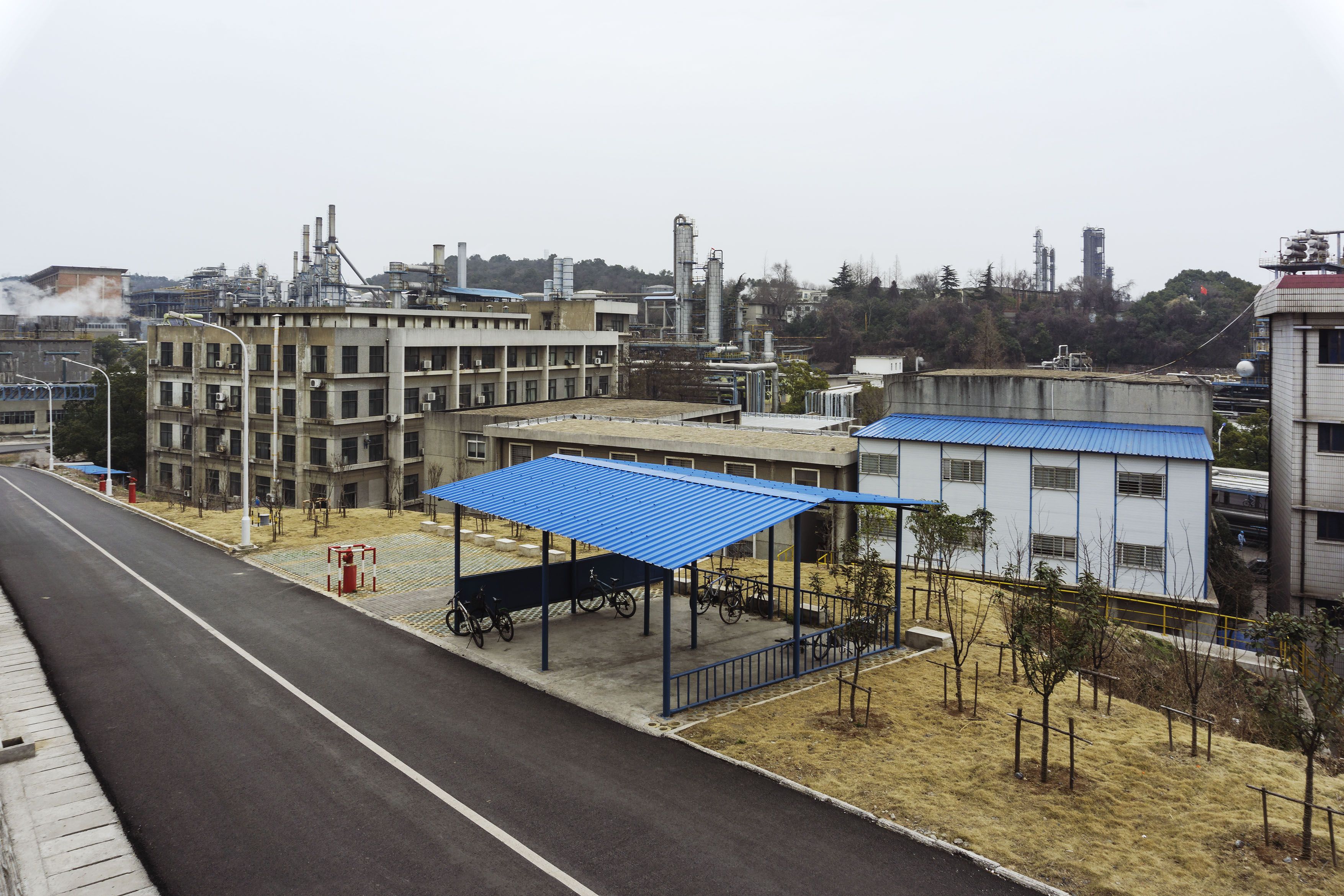 Modern industrial complex with bicycle parking under a blue metal roof.