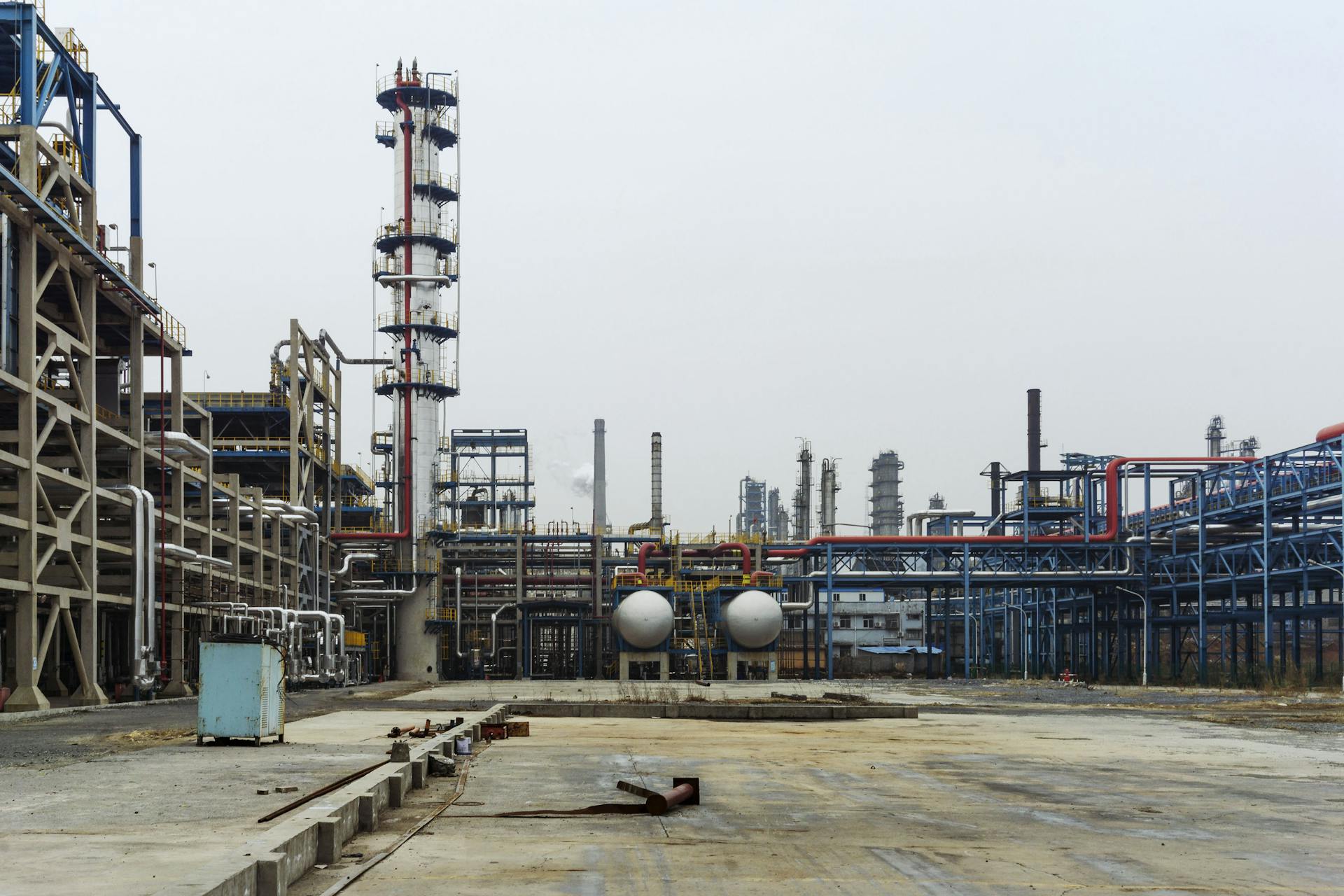 A detailed view of an industrial refinery featuring pipelines and large steel structures.