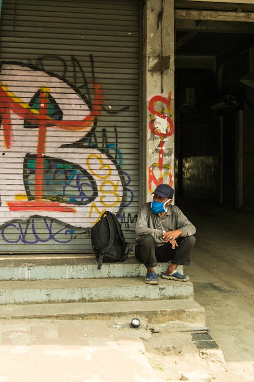 Elderly Man Sitting Beside Graffiti Wall