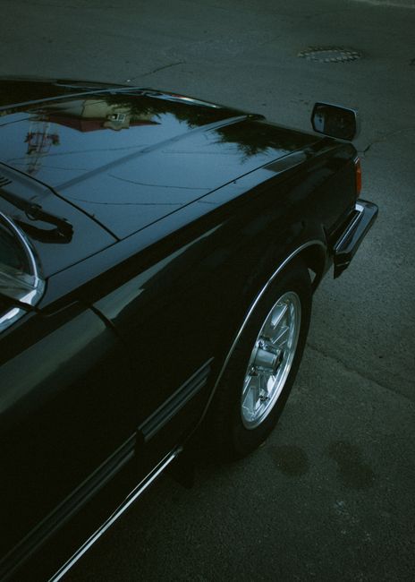 A sleek close-up of a shiny car wheel reflecting a moody sky, emphasizing elegance.