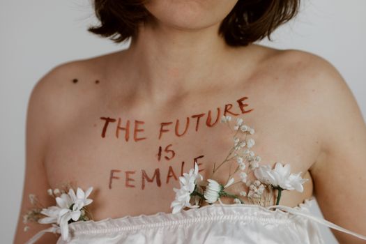 An artistic portrayal of body positivity showcasing 'The Future is Female' message adorned with white flowers.