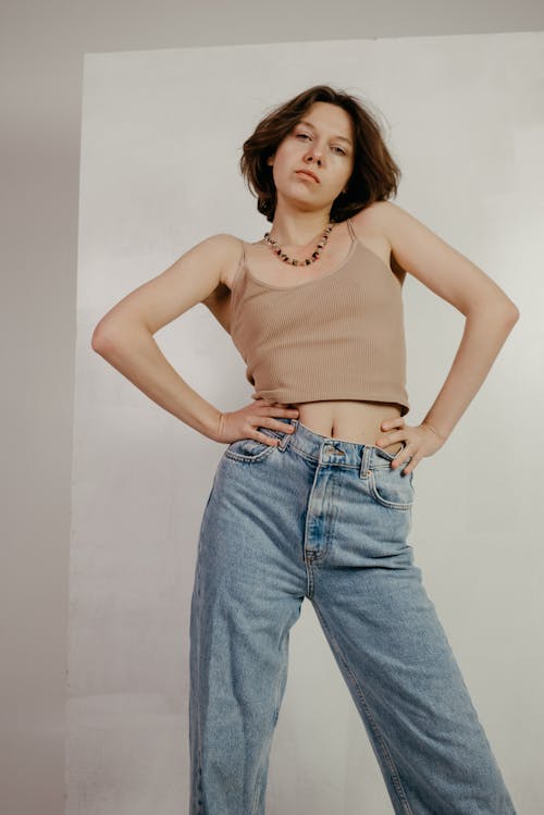 A Woman in Brown Tank Top and Denim Jeans Posing