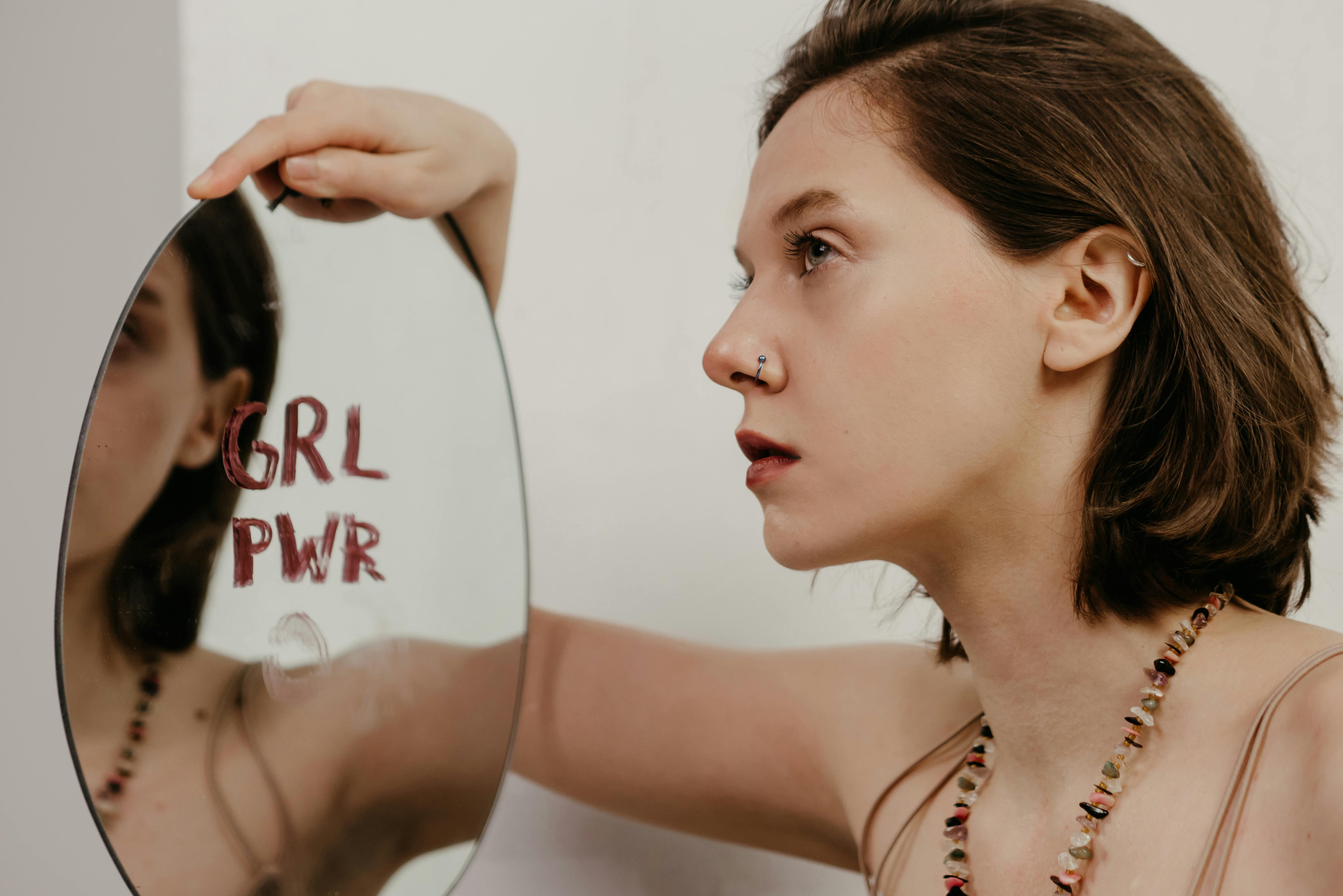 Kütüphanede kendine güvenen ve gülümseyen bir öğrenci, öğrencilik hayatında özsaygı ve kişisel gelişimi temsil eden bir görsel.