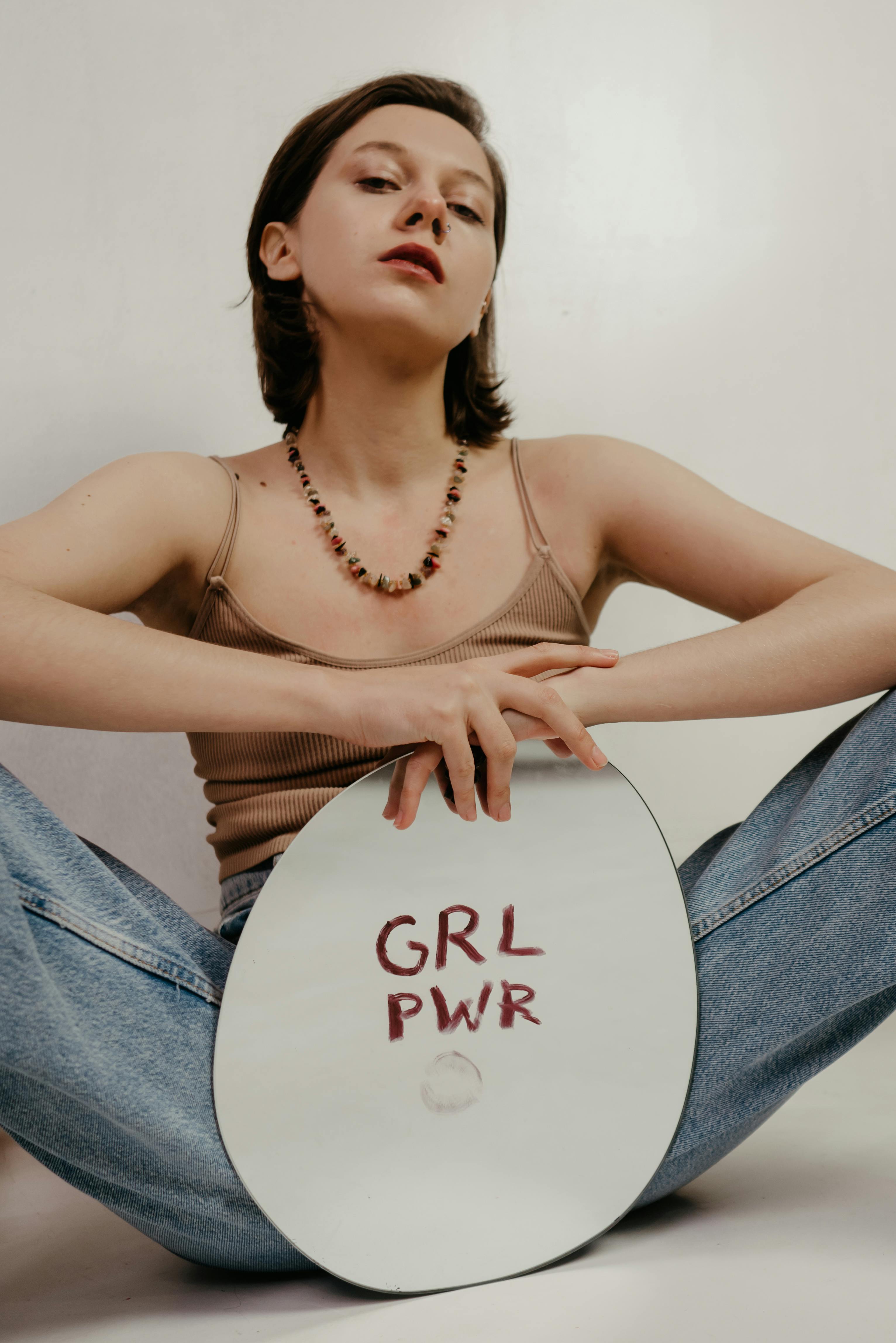 Free Woman in Brown Tank Top and Blue Denim Jeans Sitting on White Chair Stock Photo