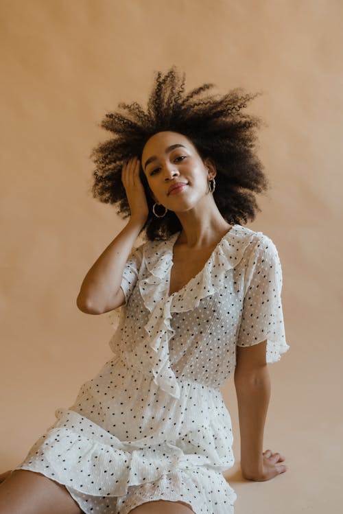 Positive young black woman relaxing in beige studio