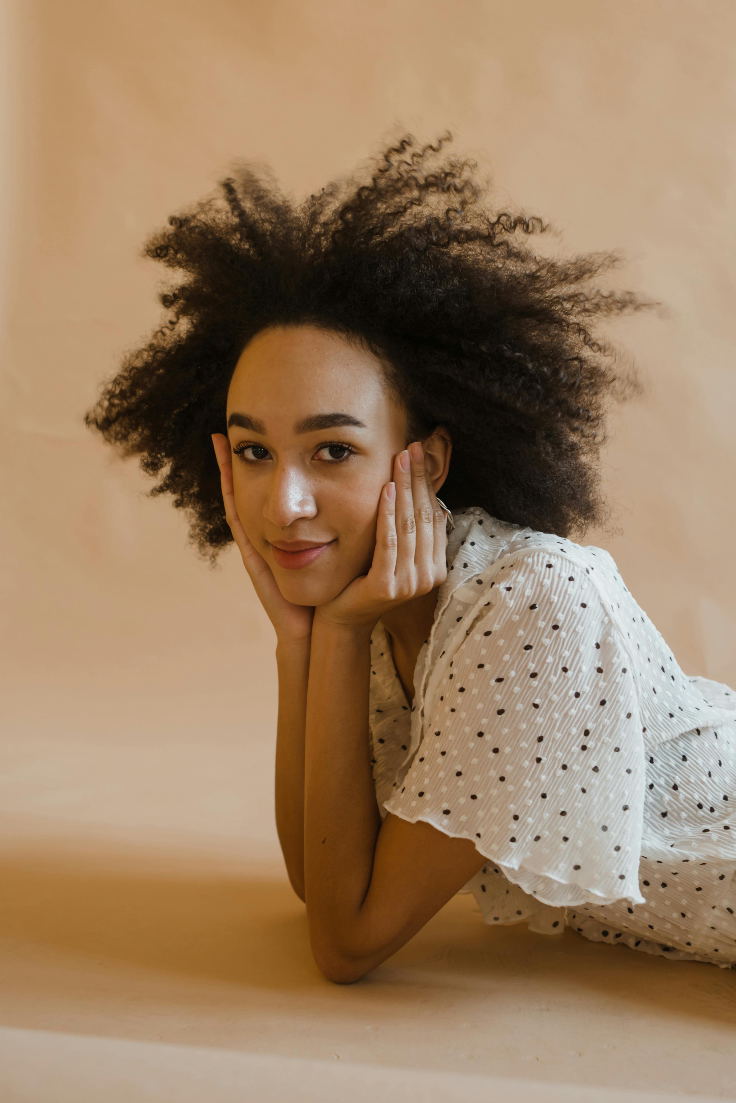 Fashion portrait of a woman with afro hair posing indoors wearing a polka dot dress.