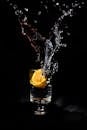黑色背景上，玻璃杯中的液体与柠檬动态飞溅