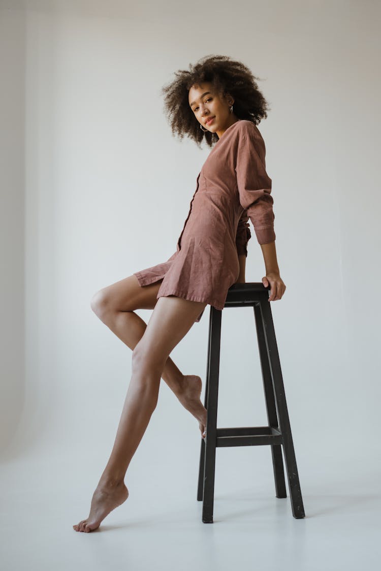 Woman In Brown Dress Sitting On A Stool