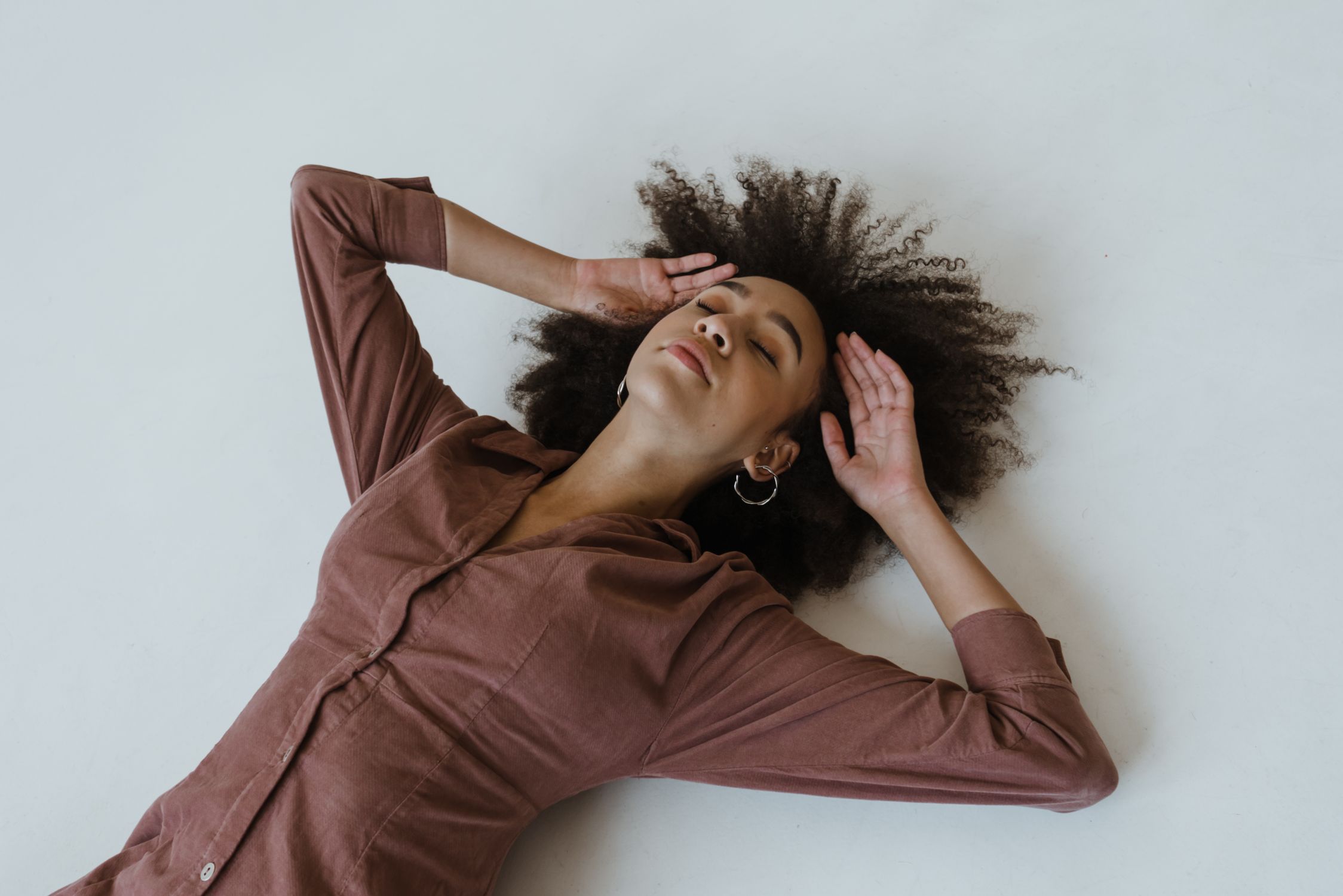 Woman in Brown Long Sleeve Shirt Lying Down on the Floor · Free Stock Photo