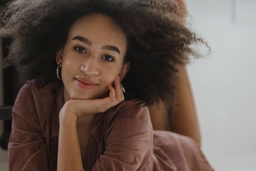 Free Charming young woman with afro hair posing confidently indoors, showcasing natural beauty and fashion. Stock Photo