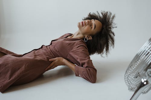 Free Woman in Brown Long Sleeve Dress Lying on White Floor Stock Photo