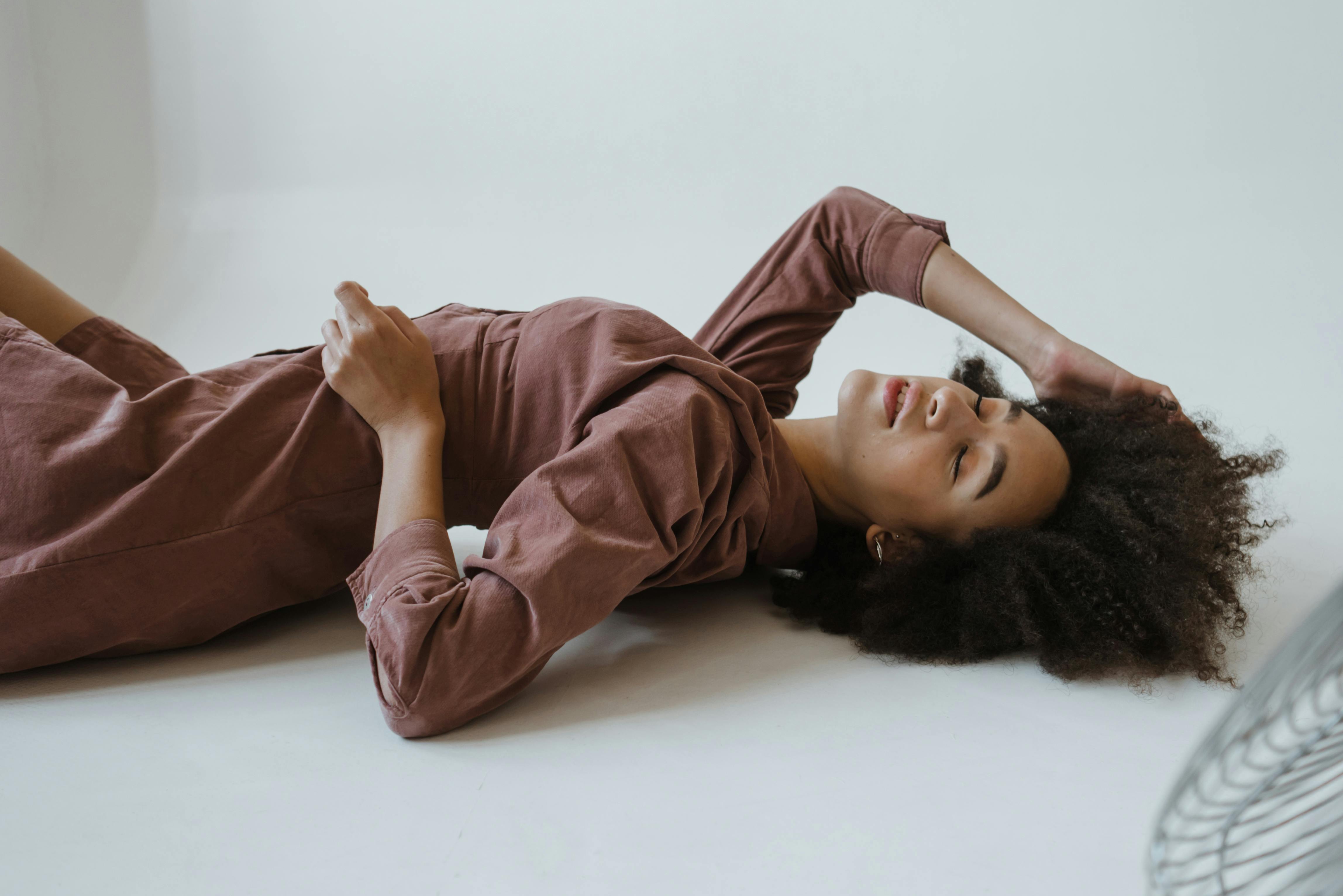 一张宁静的摄影棚照片，一位非洲裔女性闭着眼睛躺着，散发着自然之美和平静