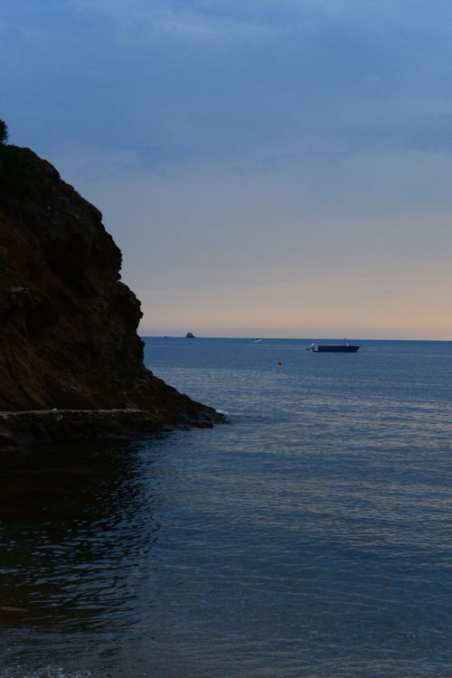 Free Peaceful coastal scene with a boat near the horizon during twilight. Stock Photo