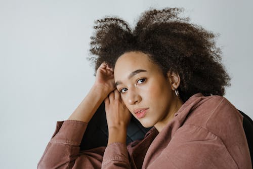 Thoughtful young black woman leaning on hand while resting in armchair