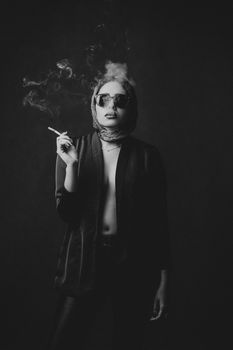 这幅黑白肖像中的时尚女性正在吸烟，传达出优雅与神秘