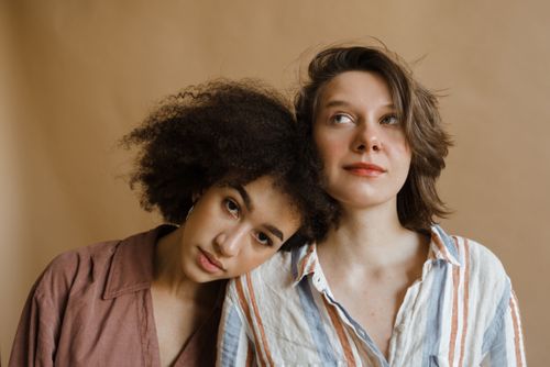 Free A close-up portrait of two women embracing with natural beauty in a studio setting. Stock Photo