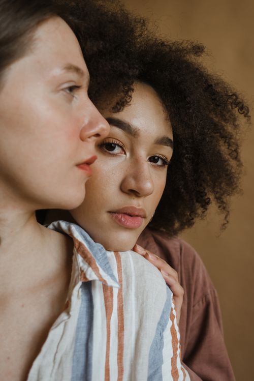 Free Artistic close-up portrait of two diverse women with natural expressions and warm earthy tones. Stock Photo