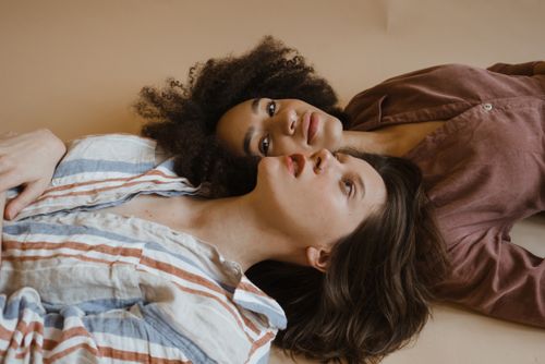 Free Two women lying down in a relaxed pose showcasing fashion and diversity indoors. Stock Photo