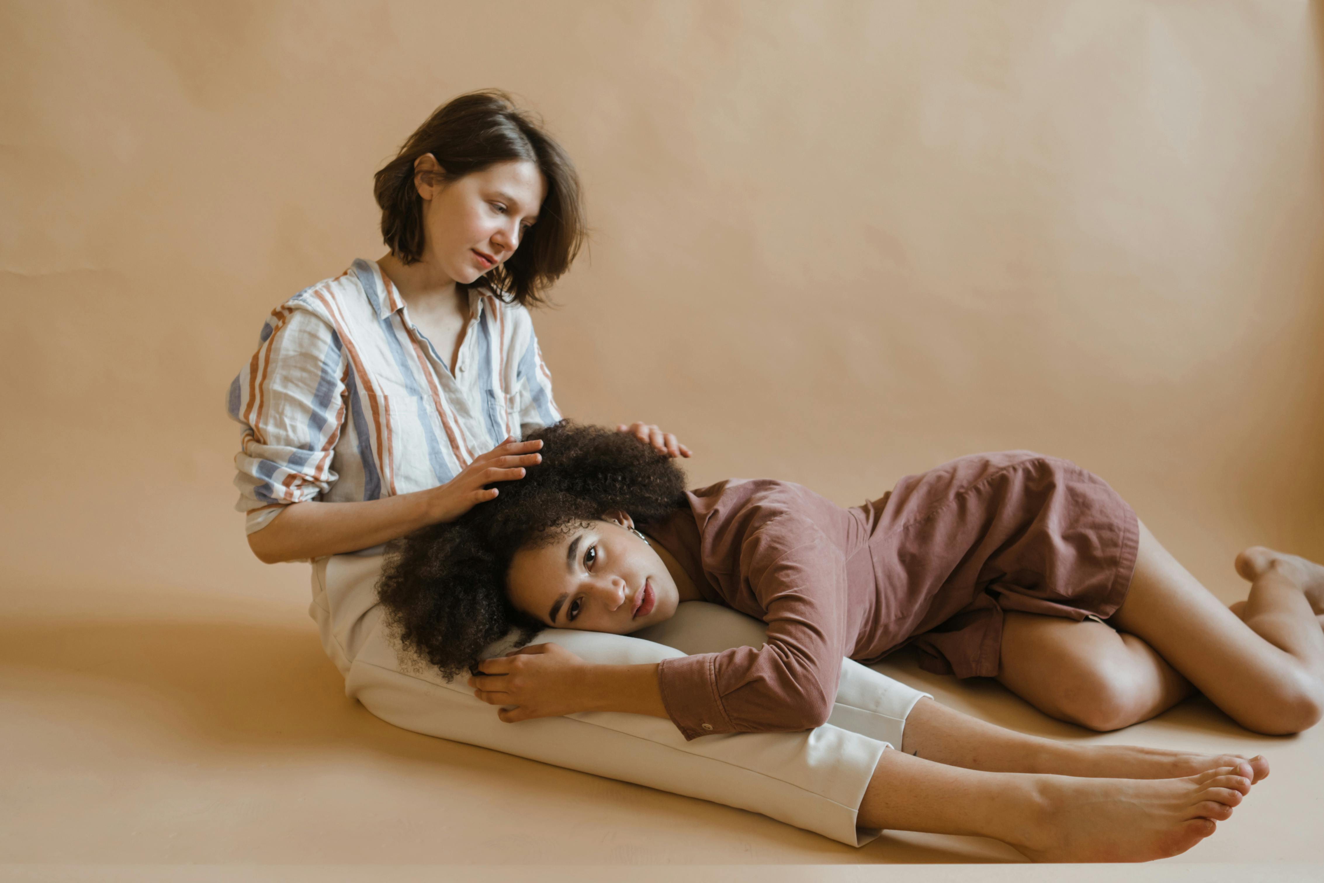 Tender studio portrait showing friendship and diversity, featuring two women embracing on a neutral backdrop.