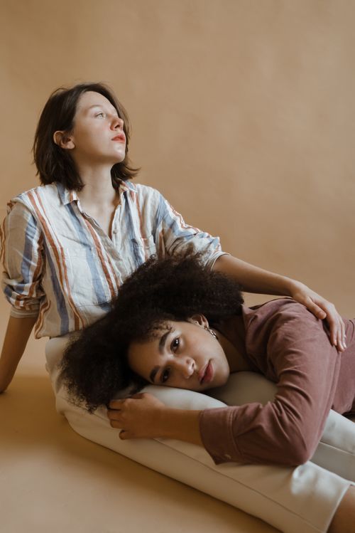 Free Two women sitting indoors against a neutral background, captured in a tranquil and relaxed mood. Stock Photo