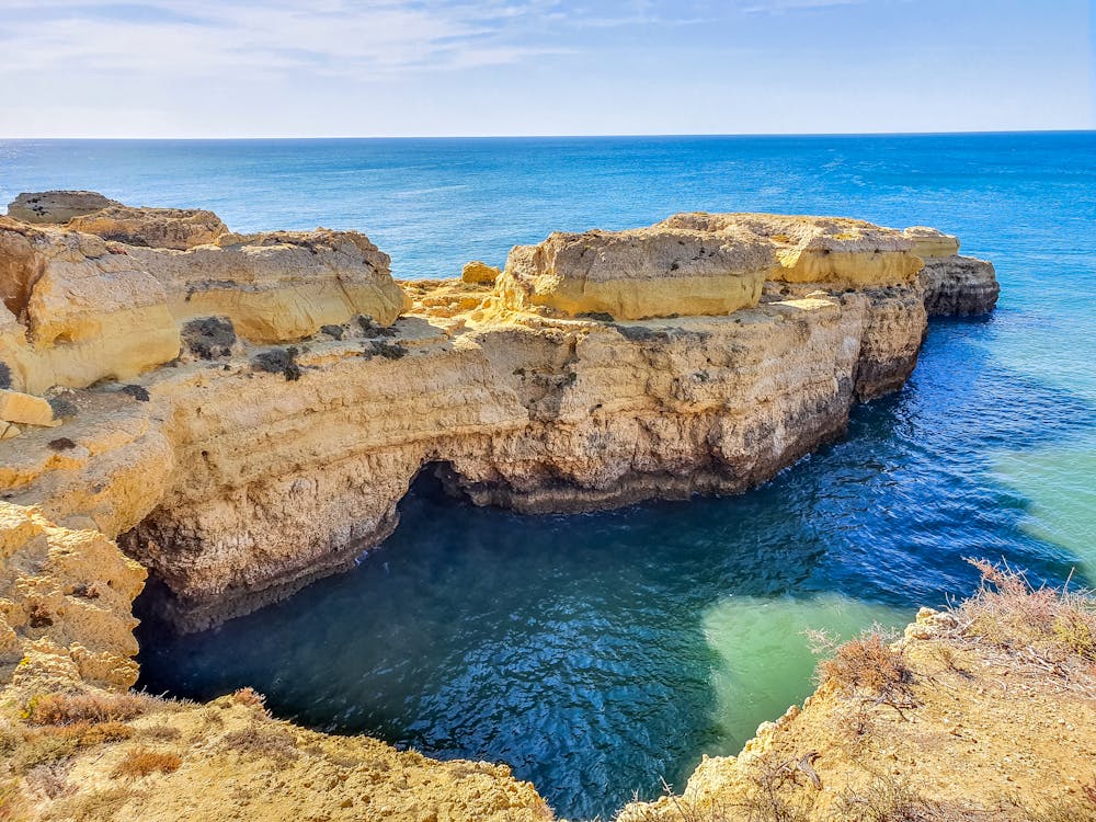 Brown Rock Formation on Blue Sea Under Blue Sky