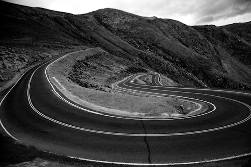 Grayscale Photo of a Road in the Middle of a Mountain