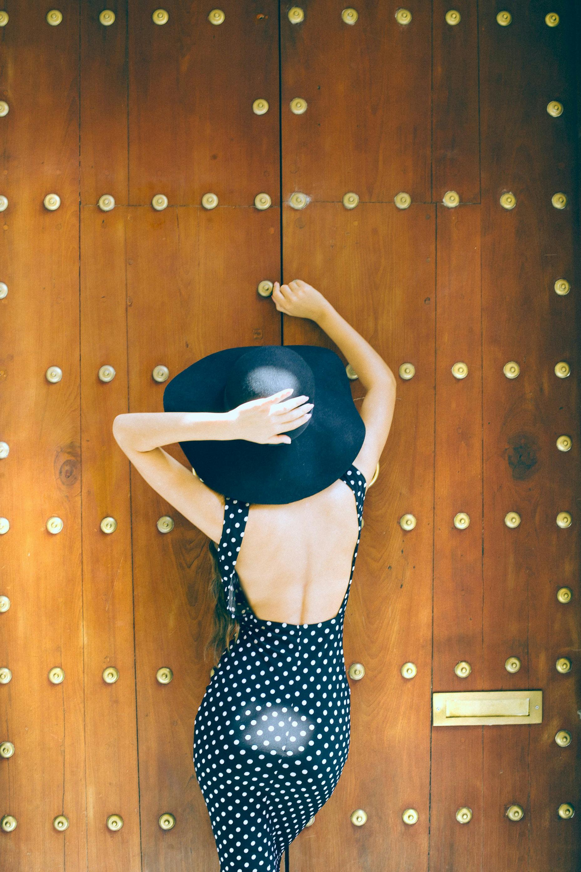 anonymous woman in hat standing near wall