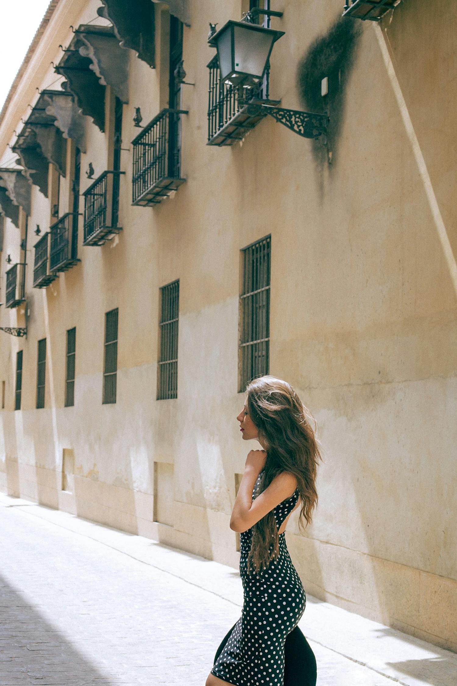 Stylish Woman In Dress Standing On Sidewalk Near Old Building · Free