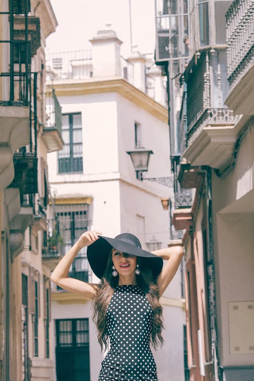 Gratis Mujer En Vestido De Lunares Blanco Y Negro Con Sombrero Negro De Pie En Las Escaleras Foto de stock