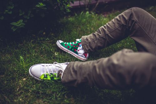 Free Relaxed scene with colorful hand-painted sneakers on grass, reflecting leisure and outdoor lifestyle. Stock Photo