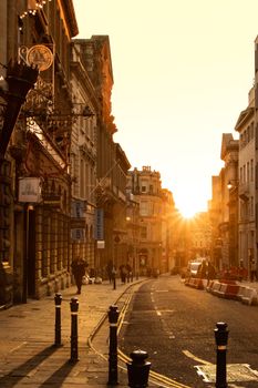Golden hour in Bristol with people walking on a historic city street as the sun sets.