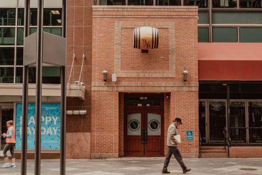 Street view of pedestrians passing a brick building with unique barrel decor.
