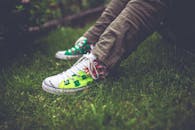 青少年穿着充满活力的运动鞋，坐在户外的绿色草坪上