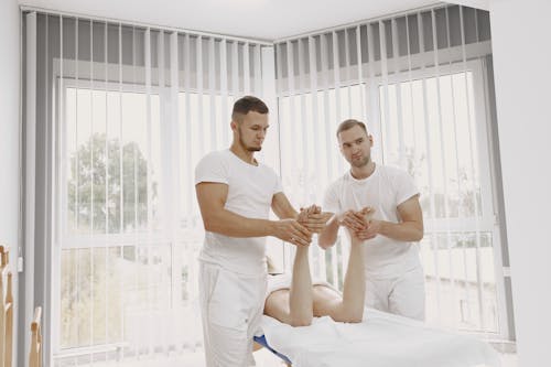 Men in White Shirts Massaging a Person's Feet
