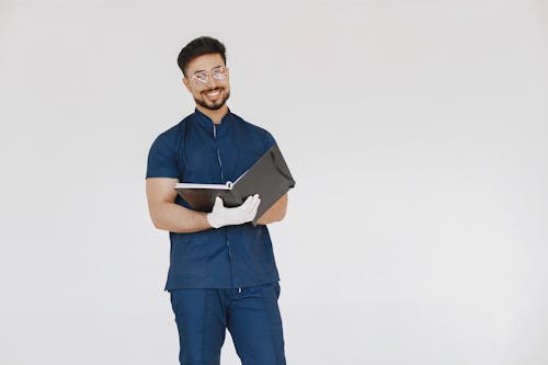 A Bearded Man in a Scrub Suit Holding a Book