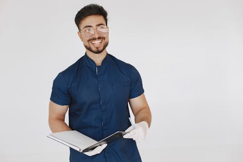 A Bearded Man in a Scrub Suit Holding a Book