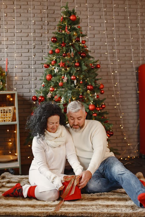 Elderly Couple Opening Gifts Beside the Christmas Tree