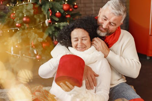 Elderly Couple Hugging while Sitting Beside the Christmas Tree