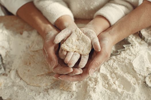 A mother and child bonding through baking, hands covered in flour while making dough.