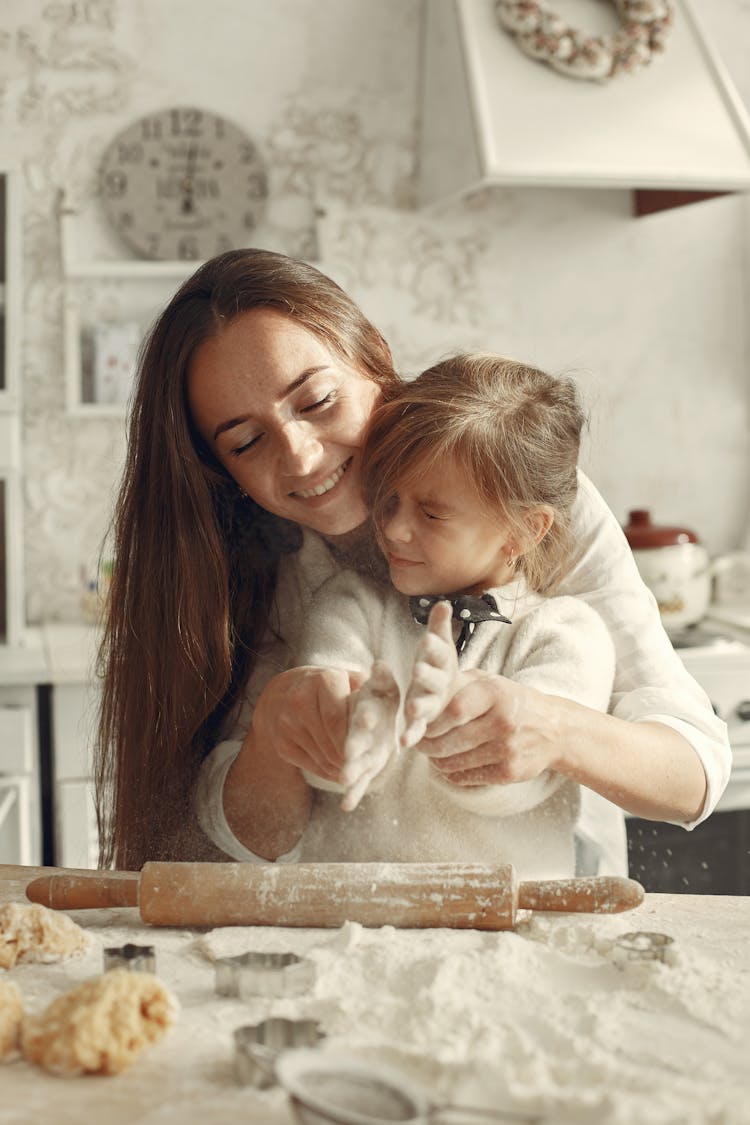 A Mother Helping Her Daughter Dust Off Flour From Her Hands