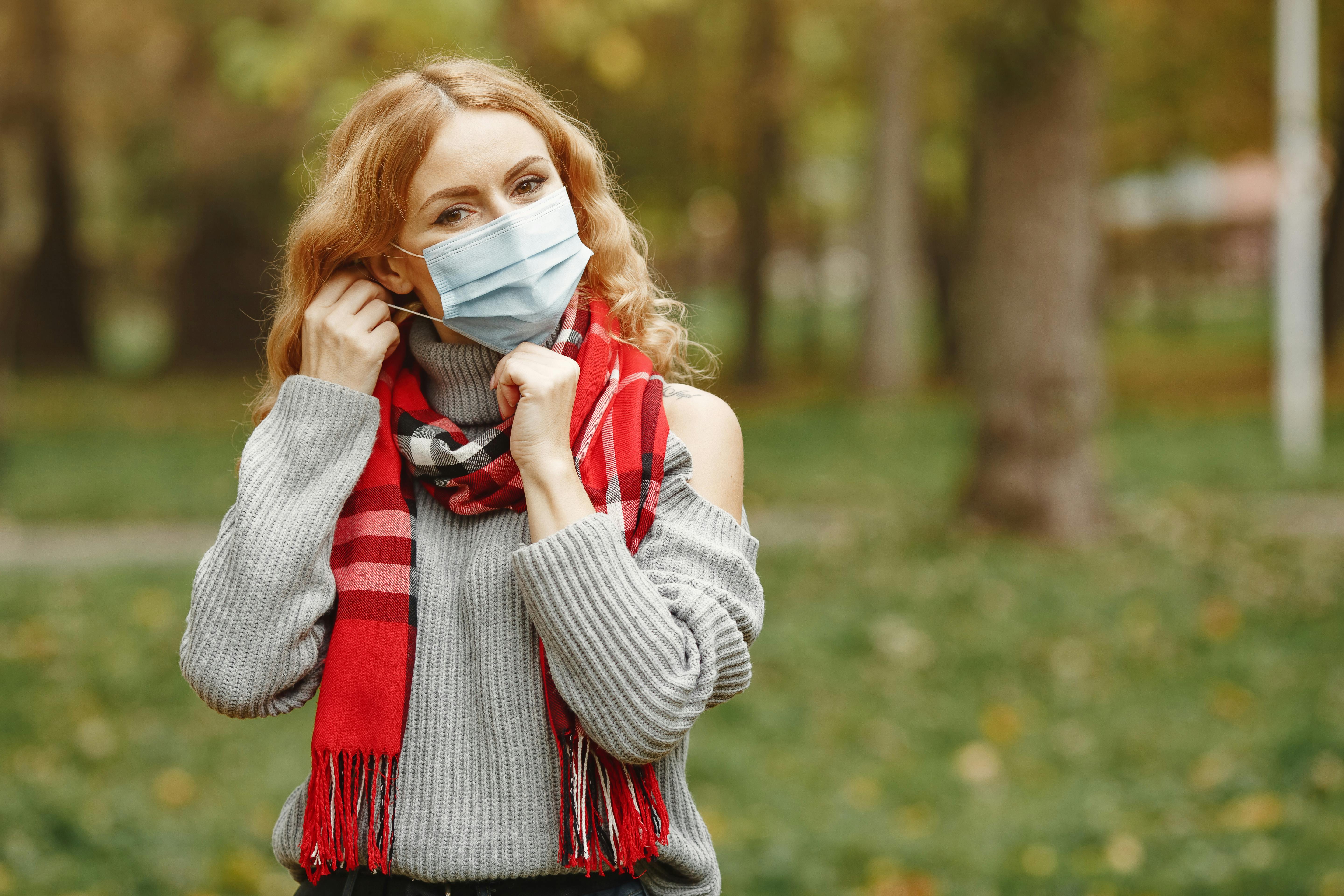 woman in gray sweater covering her face with face mask