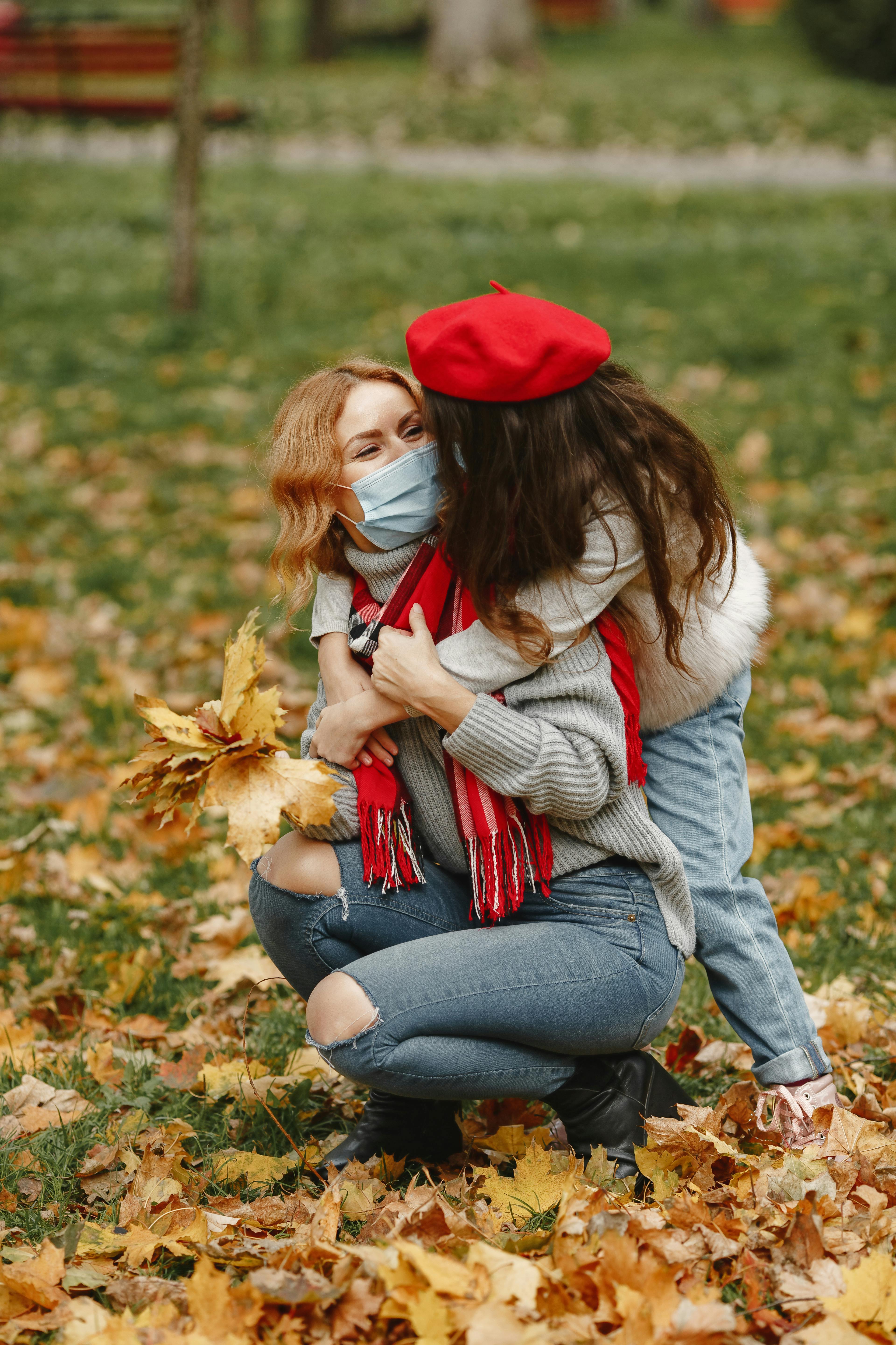 girl hugging woman in red hat and gray sweater