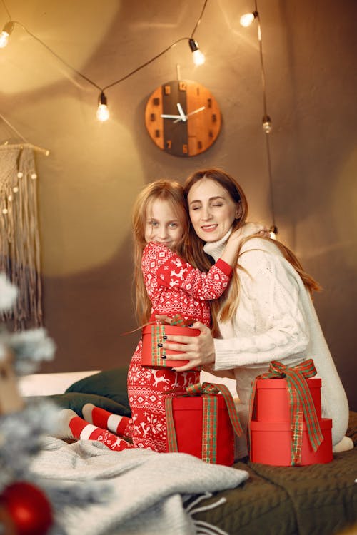 Free Mother and Daughter Hugging Over Christmas Gifts Stock Photo