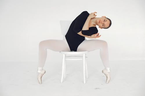 Free Ballet Dancer in Black Leotard Sitting on Chair with Open Legs Stock Photo