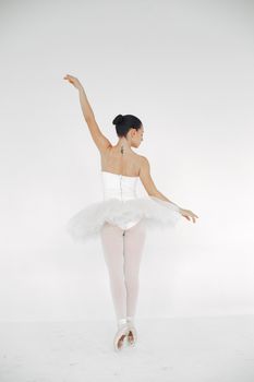 A ballerina in a white tutu on pointe showcasing her artistry in a graceful pose.