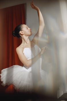 Graceful ballet dancer performing elegantly in a white tutu indoors.
