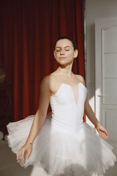 Ballet dancer posing gracefully in a white tutu with eyes closed, bathed in soft studio lighting.