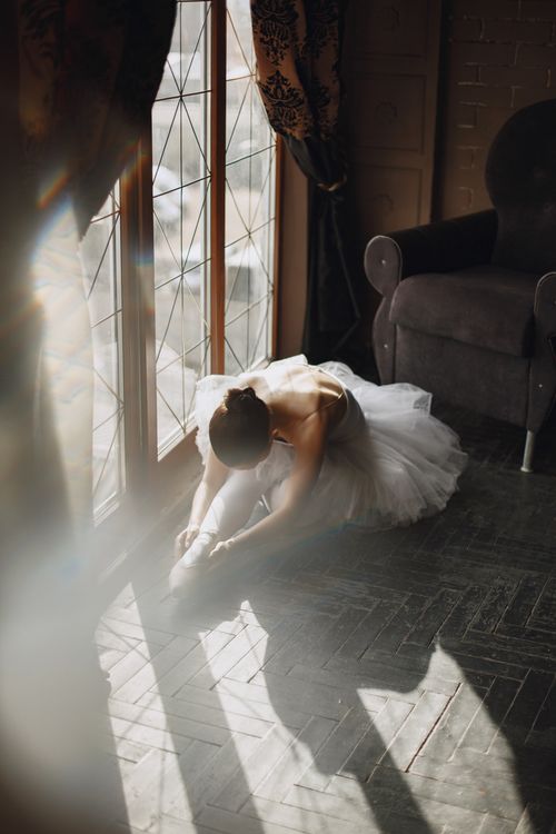 Free A graceful ballerina stretches in a sunlit room, creating a serene and artistic atmosphere. Stock Photo