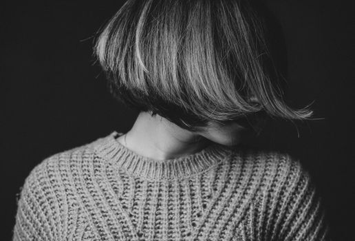一幅引人注目的黑白肖像中，一位面孔模糊、身着纹理毛衣的女子格外醒目